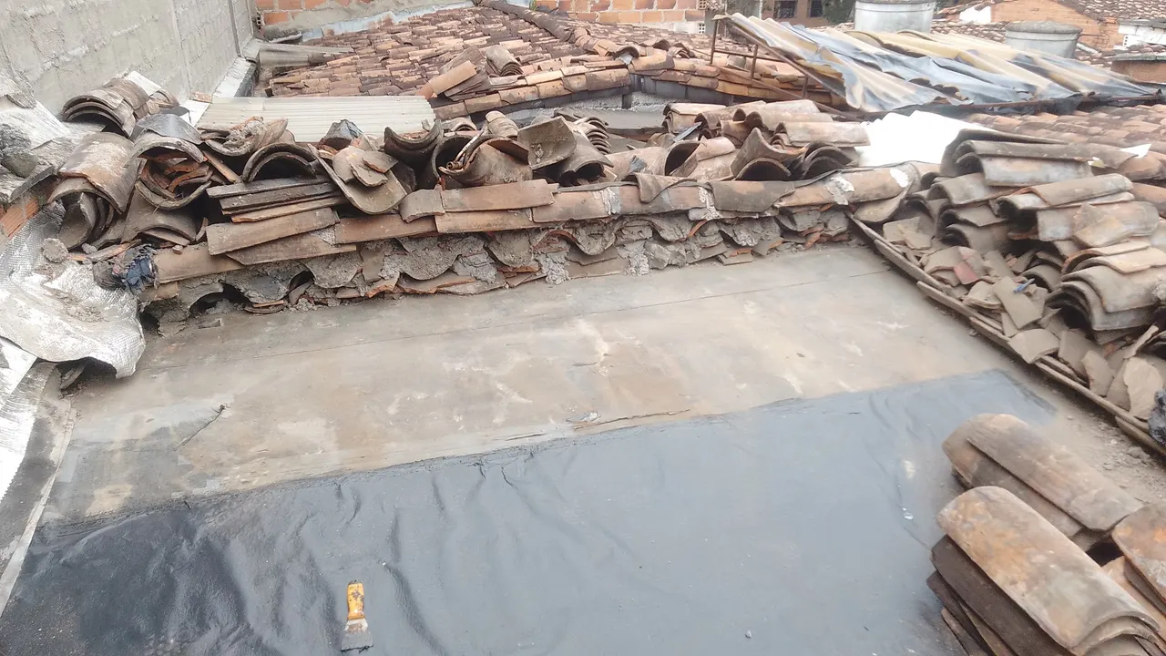 Techo con la teja de barro retirada y apilada a un lado