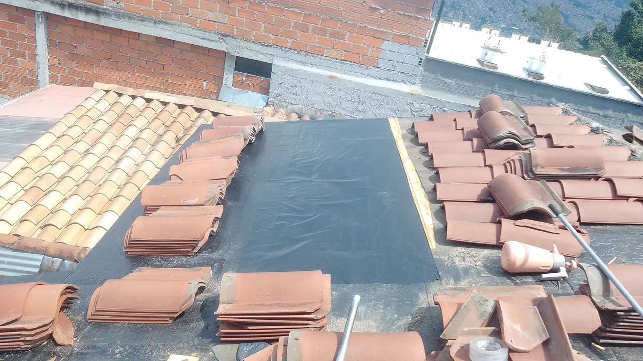 Manto negro instalado sobre la base del techo entre filas de teja